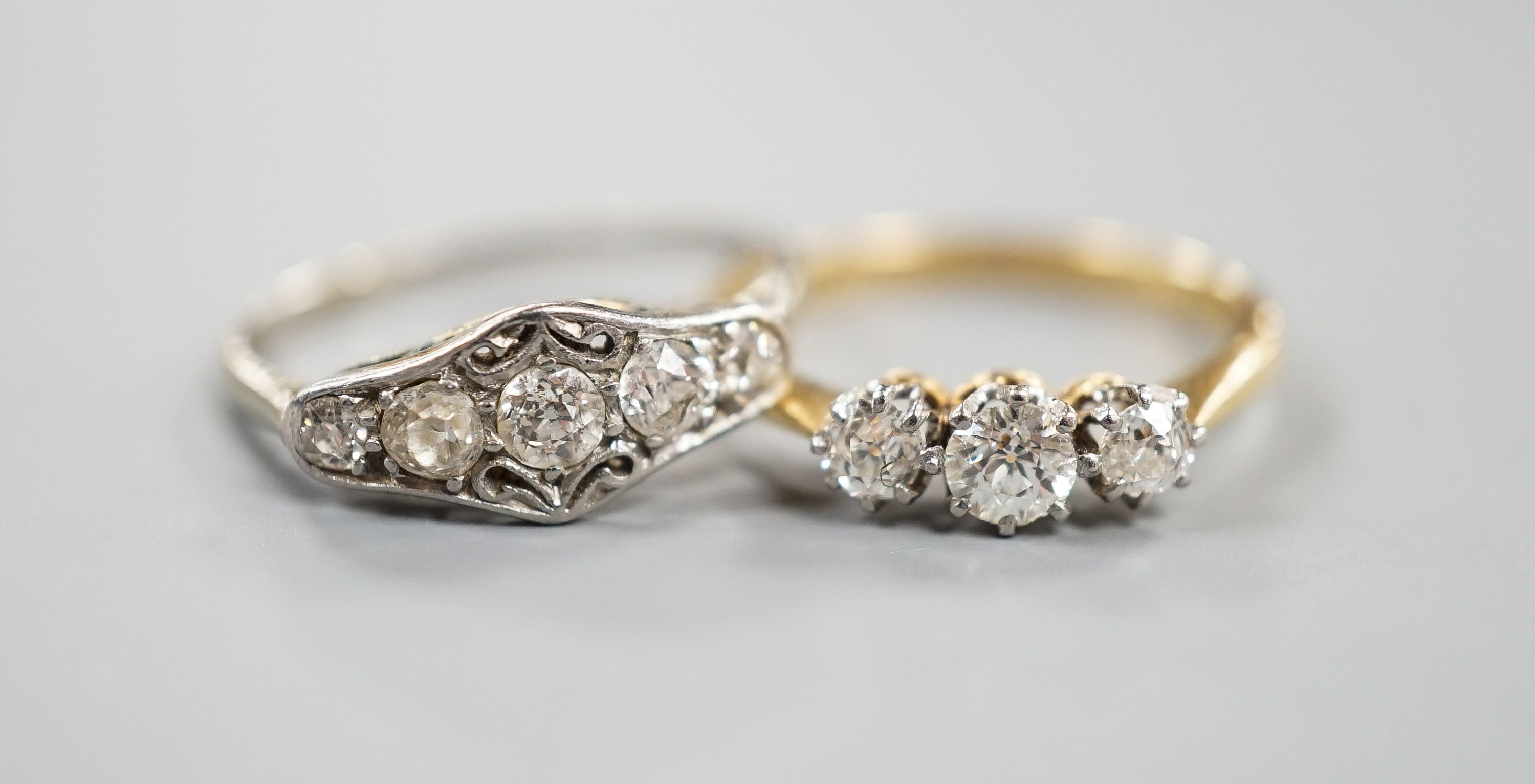 An 18ct and three stone diamond ring, size M and a white metal and graduated five stone diamond set half hoop ring, size M, gross weight 3.8 grams.